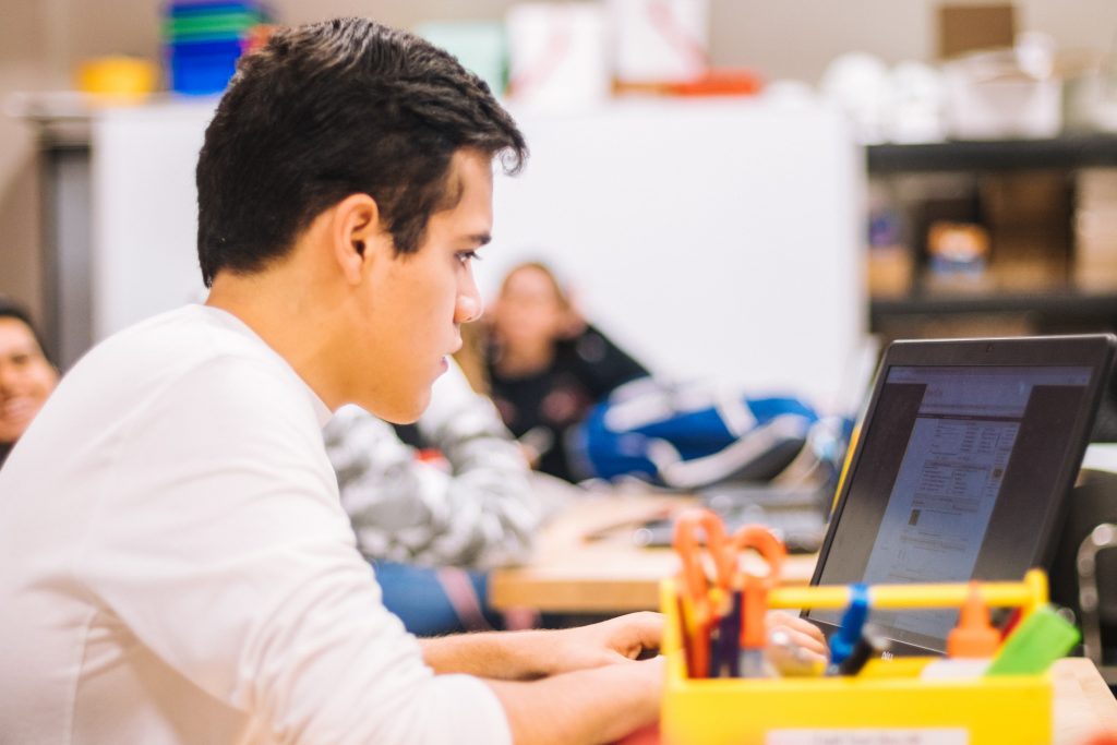 A young man sitting working on a laptop.