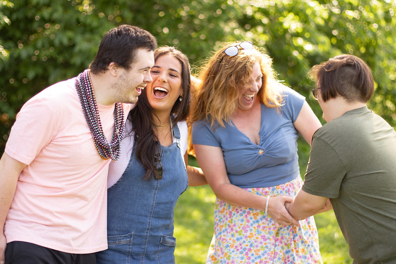 four young adults pose and smile with trees in the background